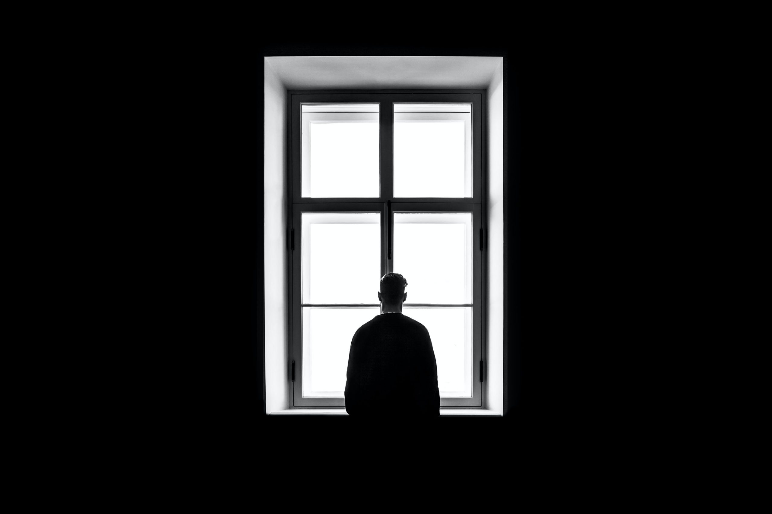 Depression Coping Skills Silhouette of man looking out of a window.