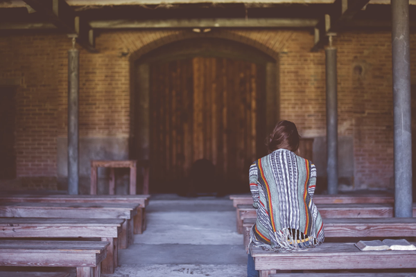 Faith Helps Deal with Anxiety & Depression Female on a church bench with Bible open beside her.